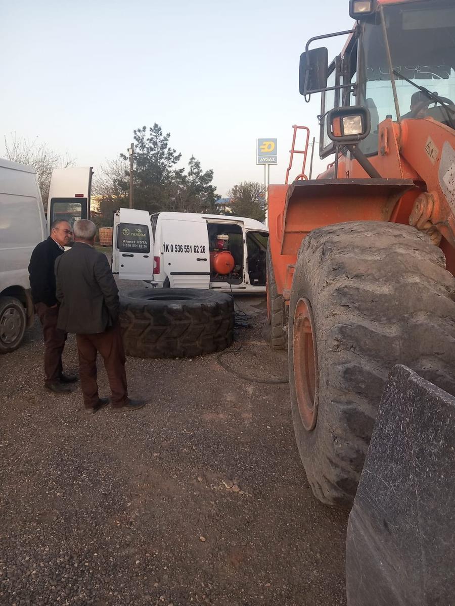 Yükleyici iş makinesinin dev lastiği ve yanında kompresörlü yol yardım aracı